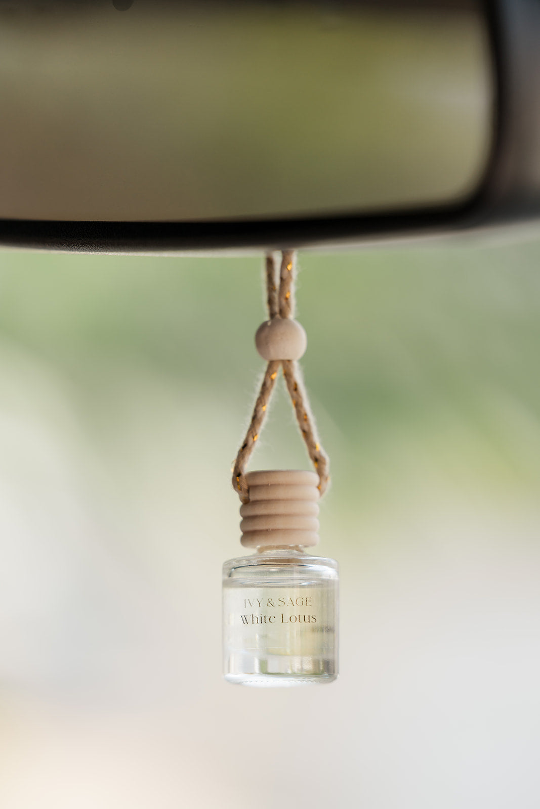 Car air freshener hanging from a car's rearview mirror with a blurred background