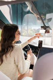 Woman sitting inside a car, holding a glass car diffuser hung on rear view mirror