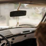 Person sitting inside a car looking out the windshield with a rearview mirror car diffuser