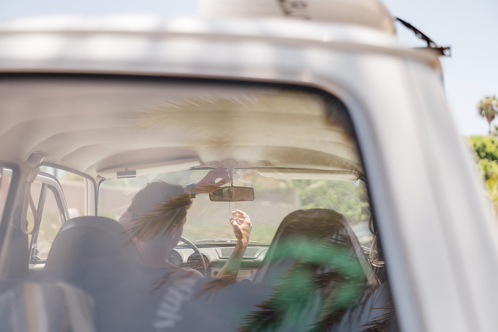 Two people sitting inside a vehicle with car diffuser hanging on rear view mirror