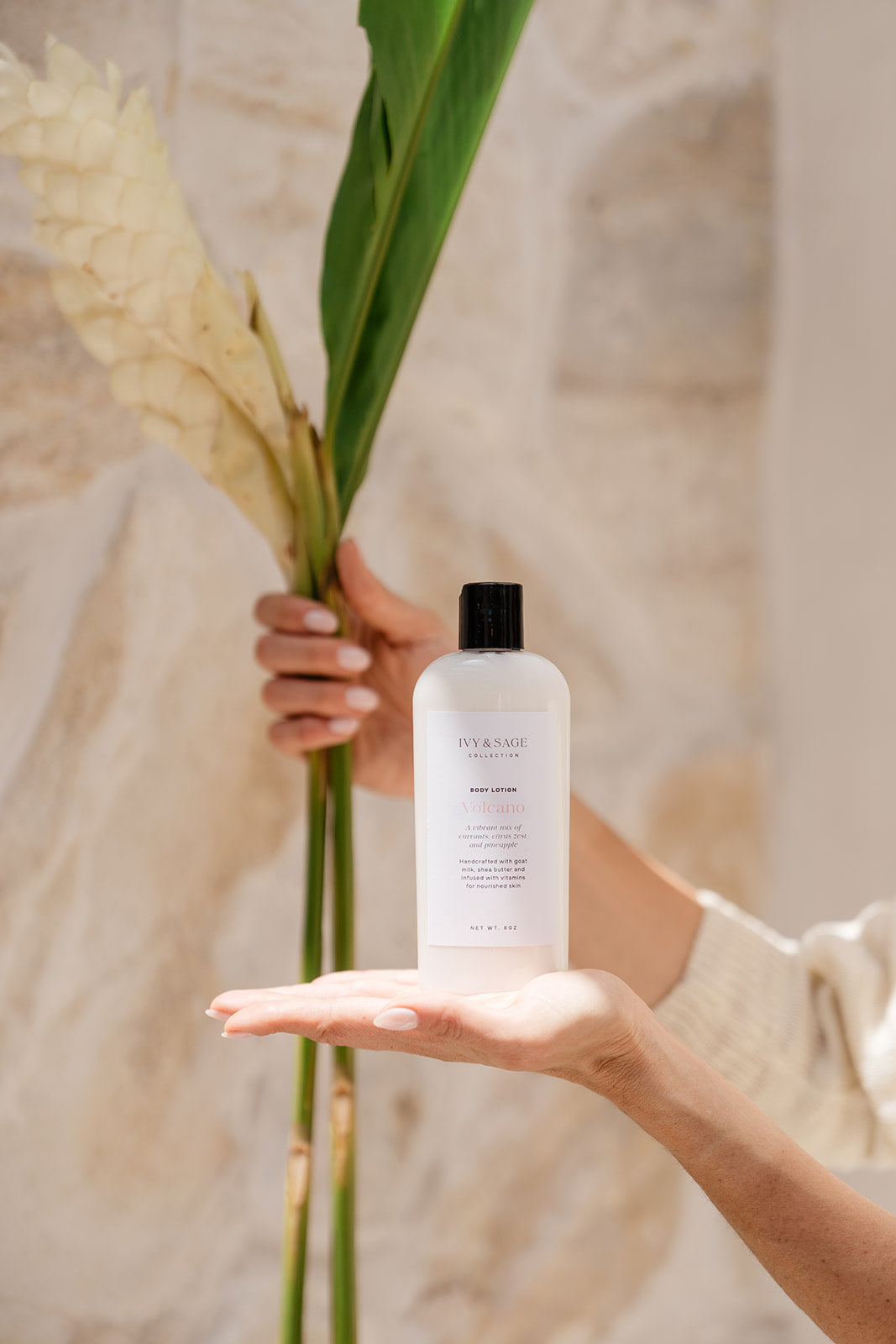 Person holding a bottle of Body Lotion skincare product with a leaf in the background
