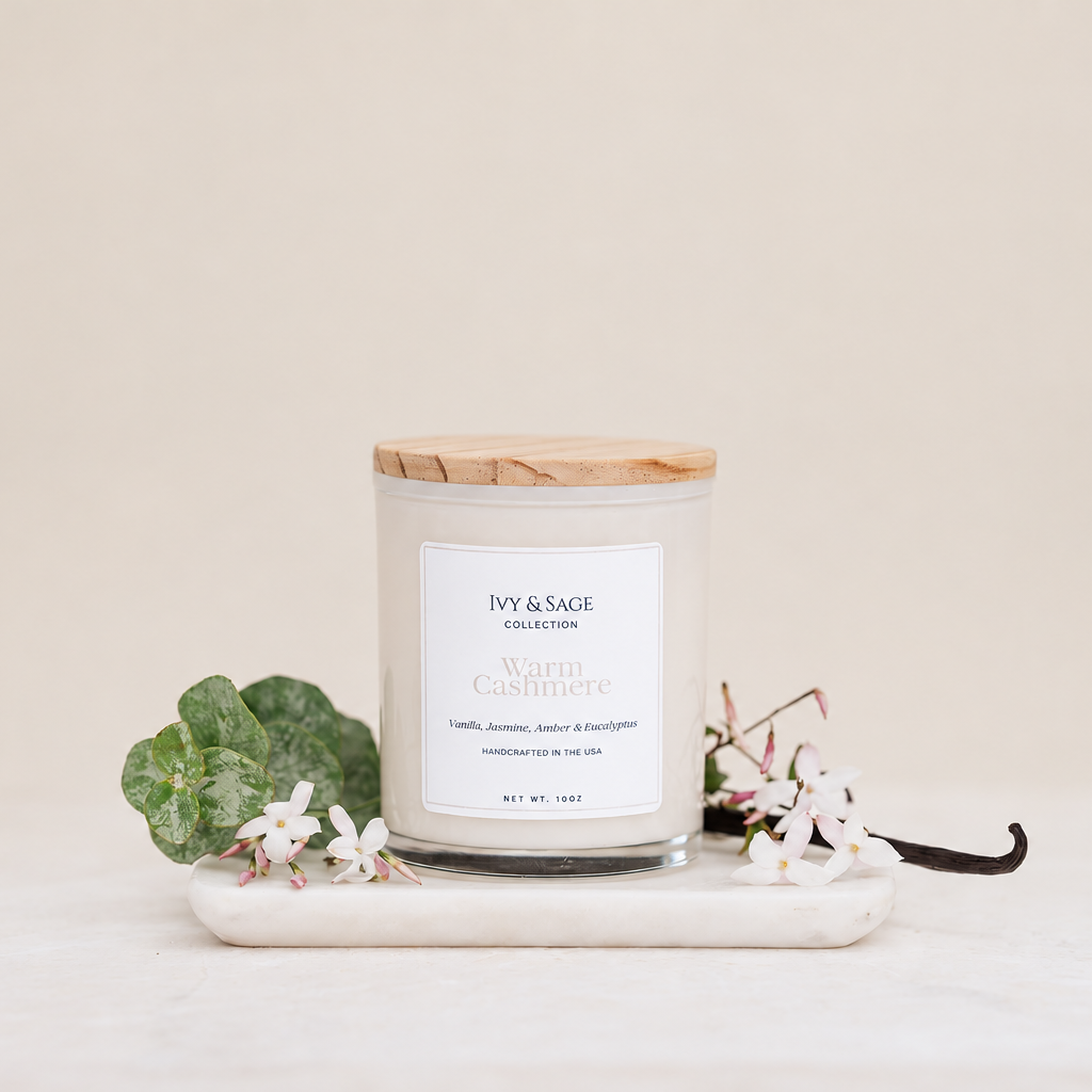 Ivy & Sage Warm Cashmere glass candle with wooden lid, styled with eucalyptus, white florals and vanilla.