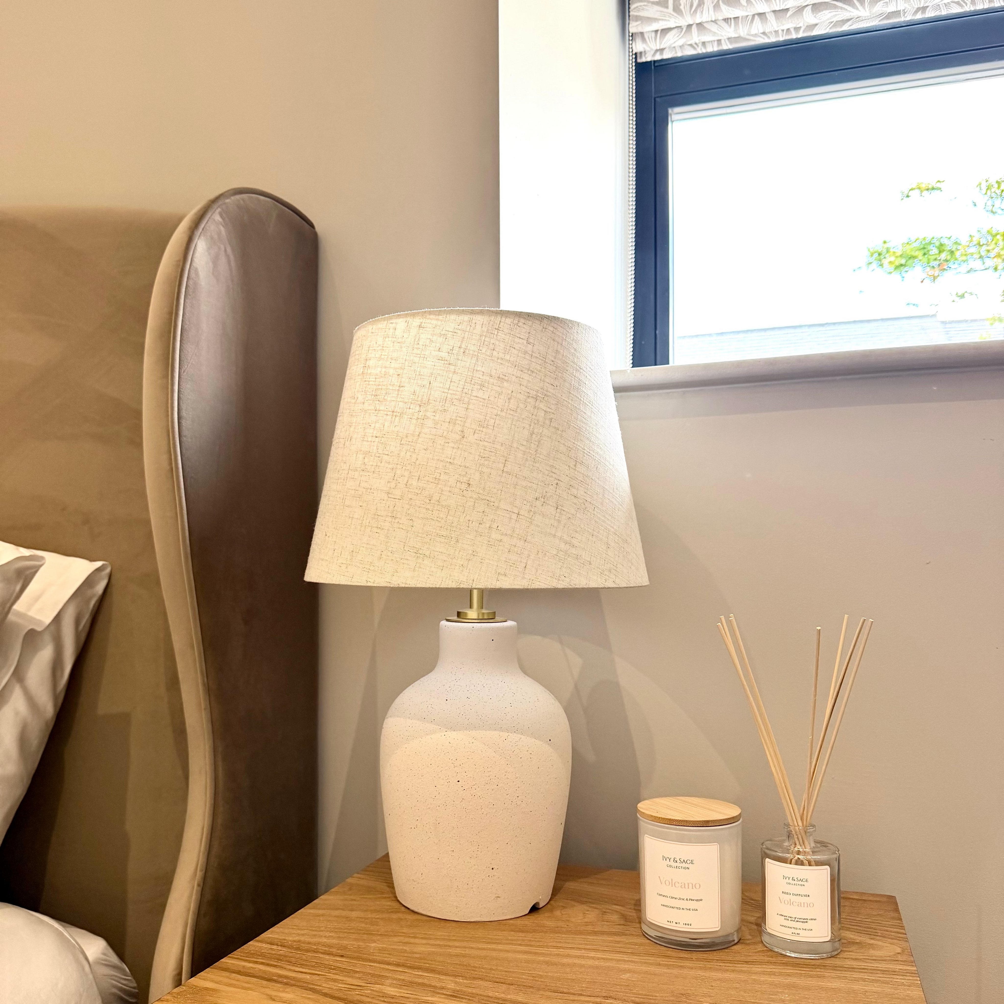 Ivy & Sage reed diffuser styled on a bedside table in a calm, neutral home interior alongside coordinating home fragrance products.