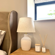 Ivy & Sage reed diffuser styled in a warm, neutral bedroom alongside coordinating home fragrance products.