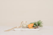 Car Diffuser glass jar with orange peel, and pine branch on a white marble slab against a beige background in Christmas Morning Scent