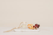 Car Diffuser Glass bottle on a white plate with orange slices and berries light beige background