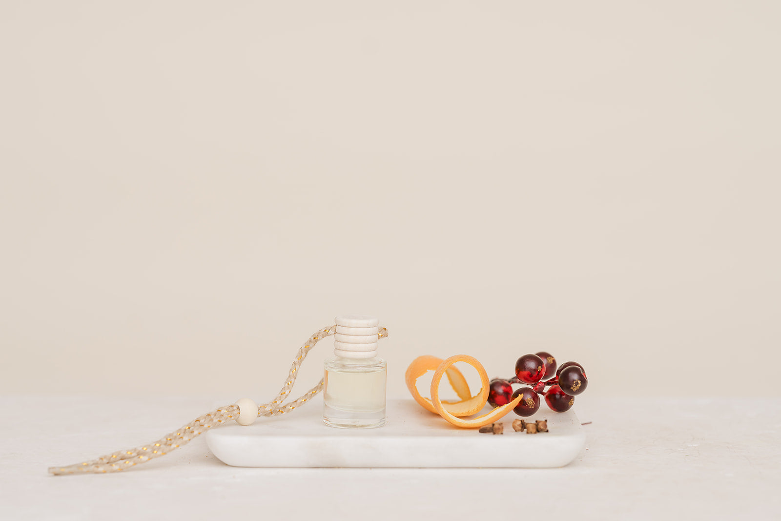 Car Diffuser Glass bottle on a white plate with orange slices and berries light beige background