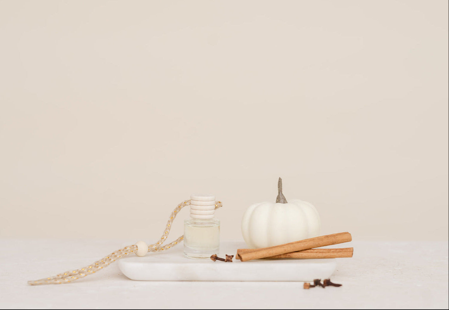 Glass Car Diffuser bottle with white pumpkin, cinnamon sticks on a white surface with a beige background in scent Pumpkin Spice