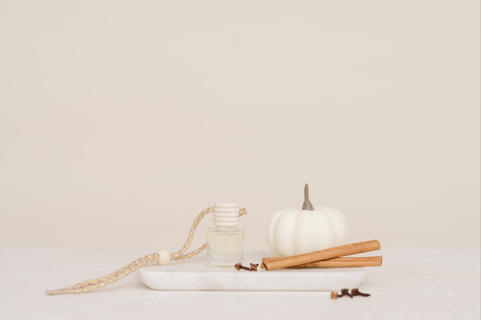 Glass Car Diffuser bottle with white pumpkin, cinnamon sticks on a white surface with a beige background in scent Pumpkin Spice