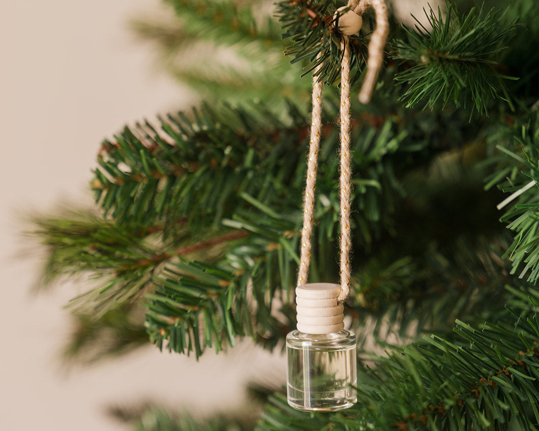 Small glass pine scented diffuser ornament hanging on a Christmas tree