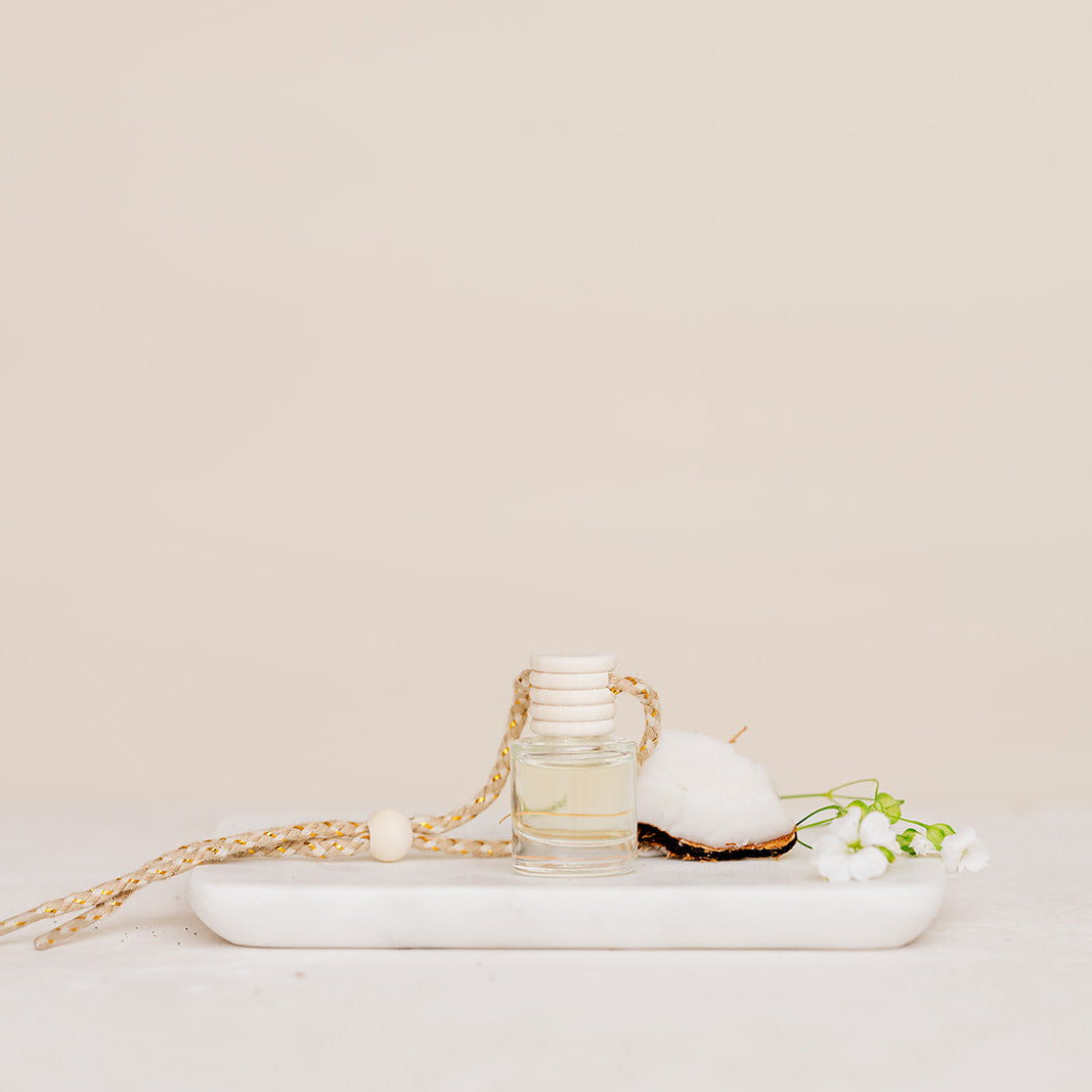 Small glass Car Diffuser bottle on a marble tray against a beige background