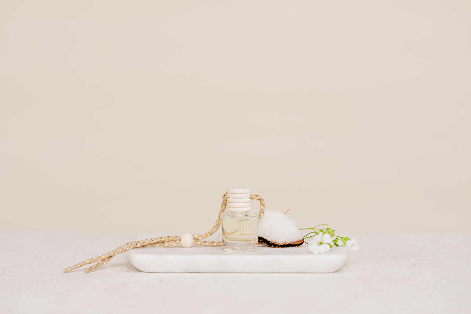 Small glass Car Diffuser bottle on a marble tray against a beige background