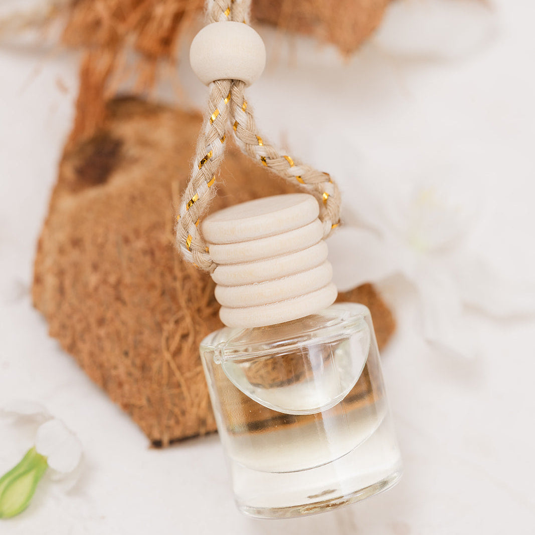 Car Diffuser glass bottle resting on coconut on beige background