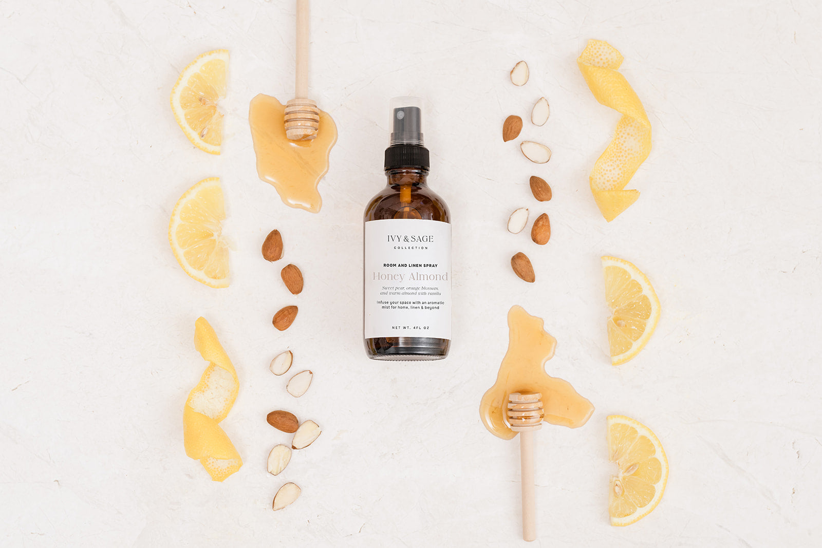 Bottle of Room & Linen Spray surrounded by lemons, honey and almonds on a white background