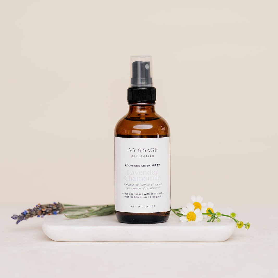 Bottle of Iyy & Sage product on a marble tray with lavender and flowers on a beige background