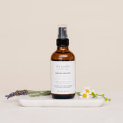 Bottle of Iyy & Sage product on a marble tray with lavender and flowers on a beige background