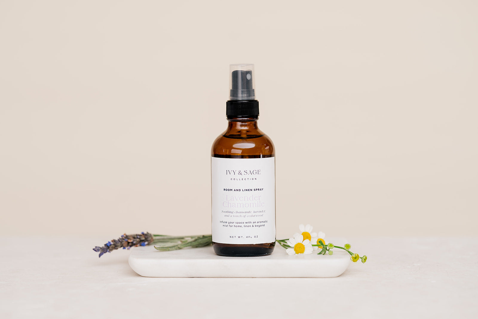 Bottle of Iyy & Sage product on a marble tray with lavender and flowers on a beige background