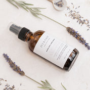 A bottle of Ivy & Sage spray with lavender and flowers on a light background