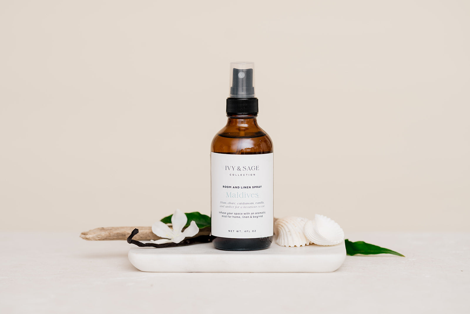 Room & Linen Spray bottle on a white surface with decorative elements such as vanilla and sea shells