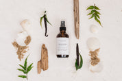 Room & Linen Spray with natural elements on a white background such as sea shells and sand