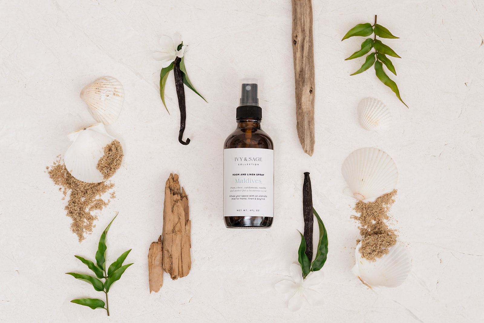 Room & Linen Spray with natural elements on a white background such as sea shells and sand
