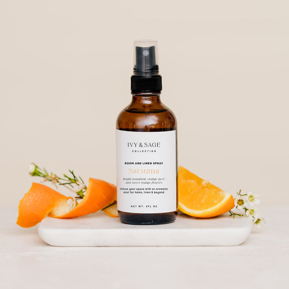 Bottle of Room & Linen Spray on a white plate with orange slices on a beige background