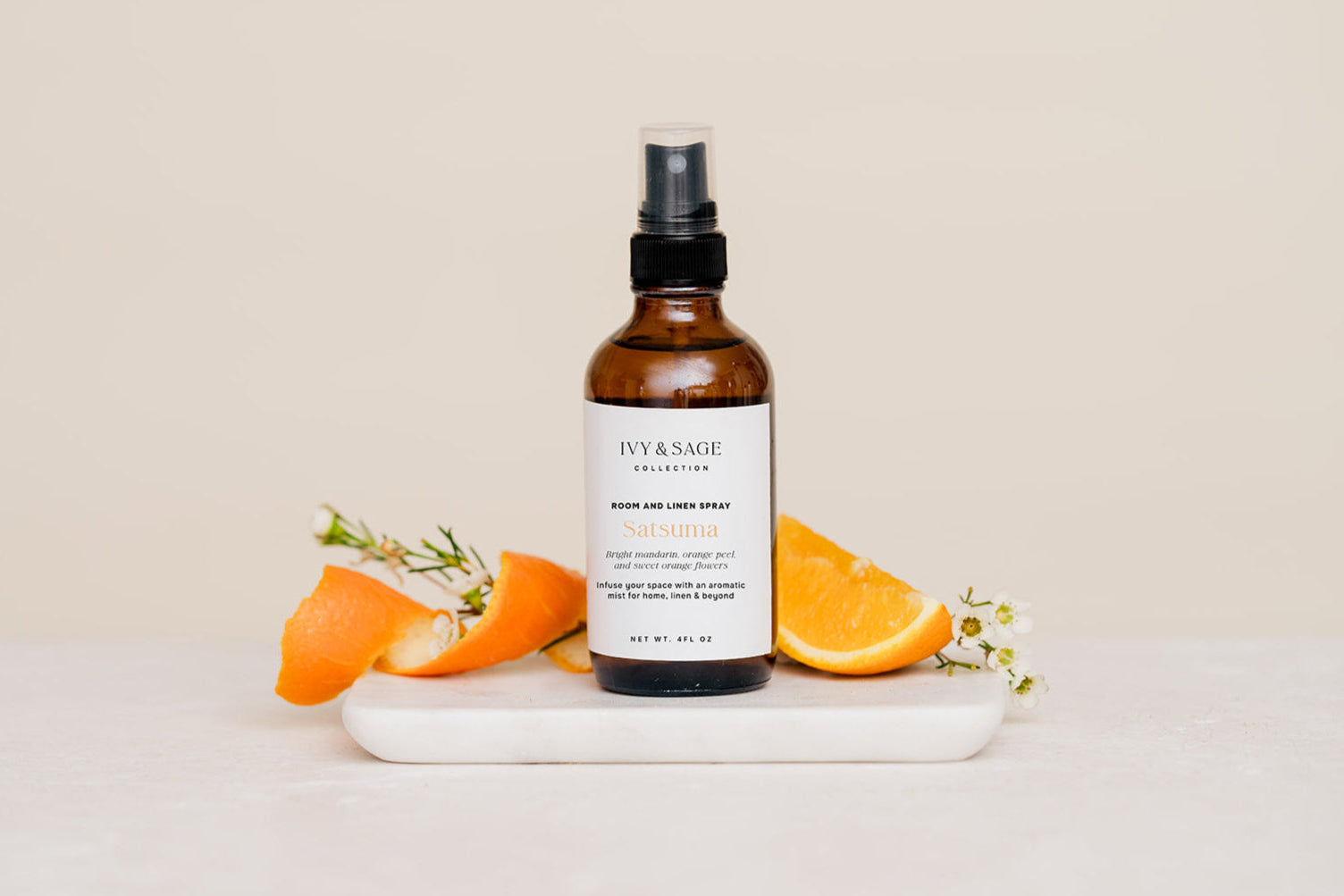 Bottle of Room & Linen Spray on a white plate with orange slices on a beige background