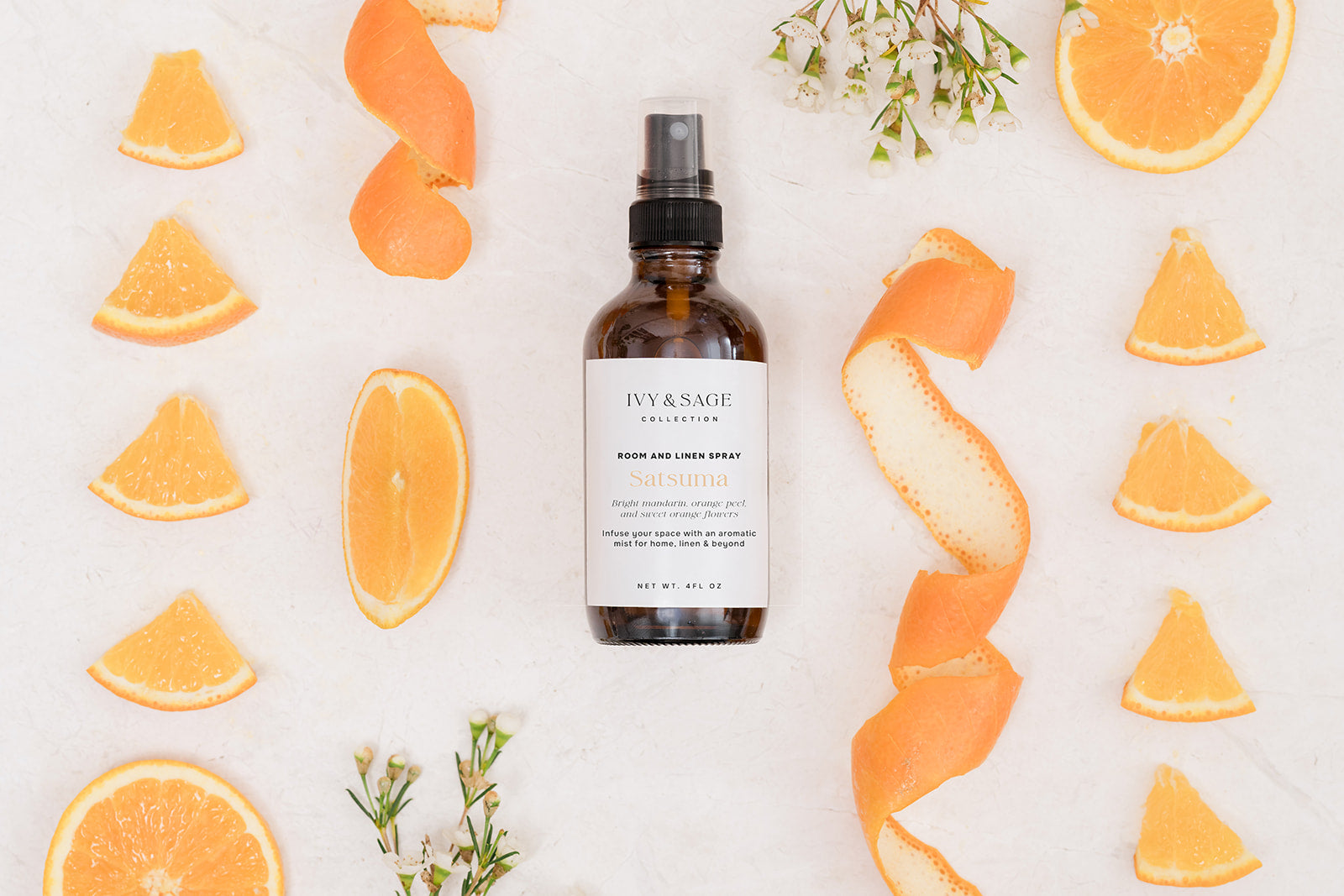 Bottle of Room & Linen Spray surrounded by orange slices and peels on a light background