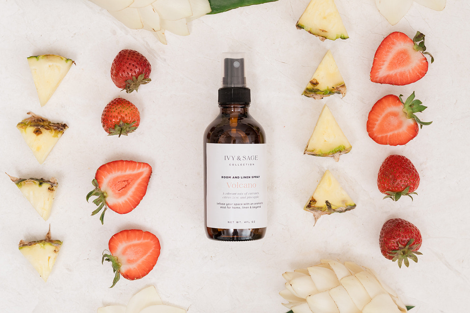 Bottle of Room & Linen pray on a white background with sliced pineapples and strawberries.