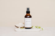 Room & Linen Spray with coconut and flowers on white marble slab