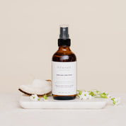 Room & Linen Spray with coconut and flowers on white marble slab