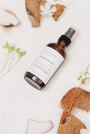 Room & Linen spray bottle with a label on a white surface with coconuts and flowers.