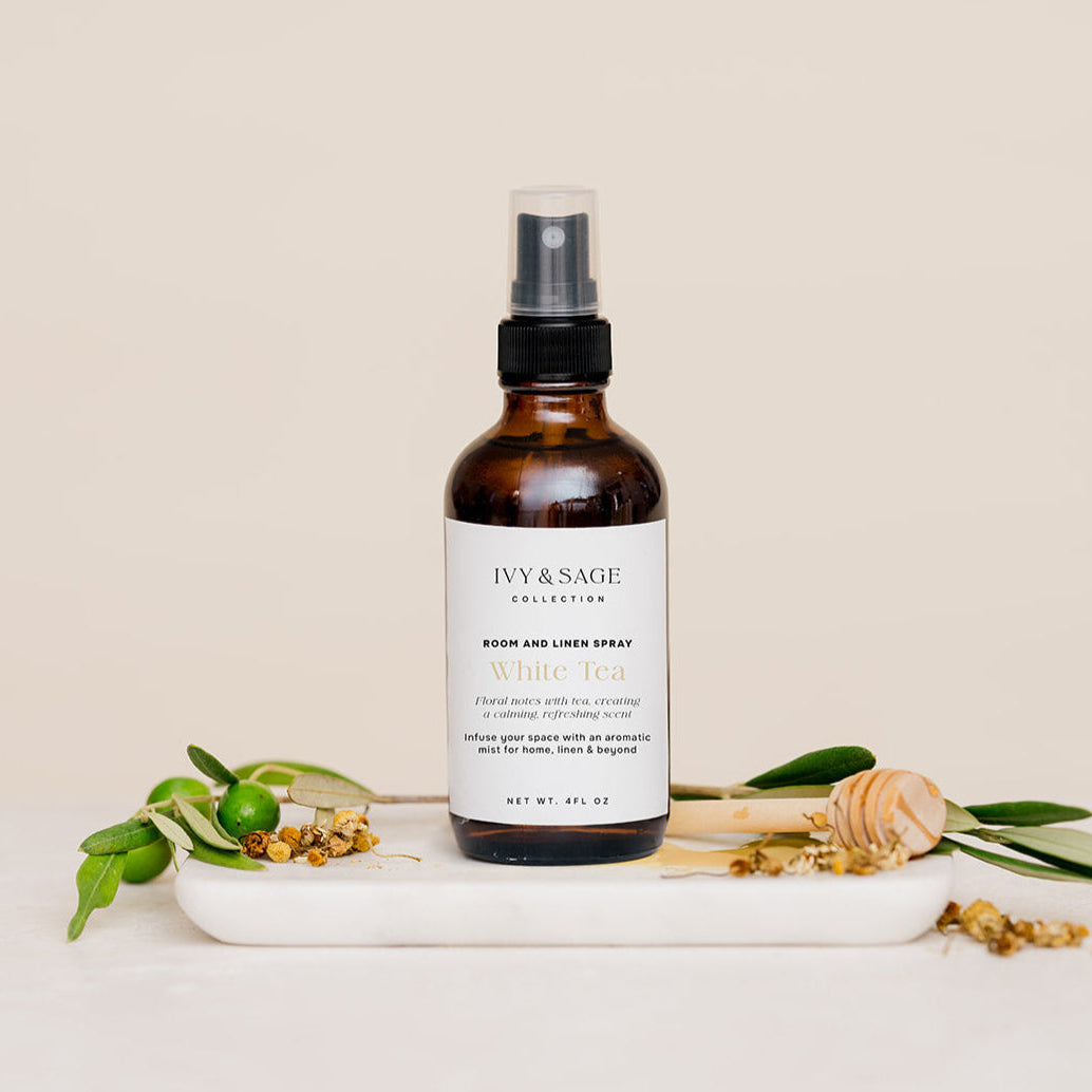 Room & Linen Spray with honey and white tea on white marble slab