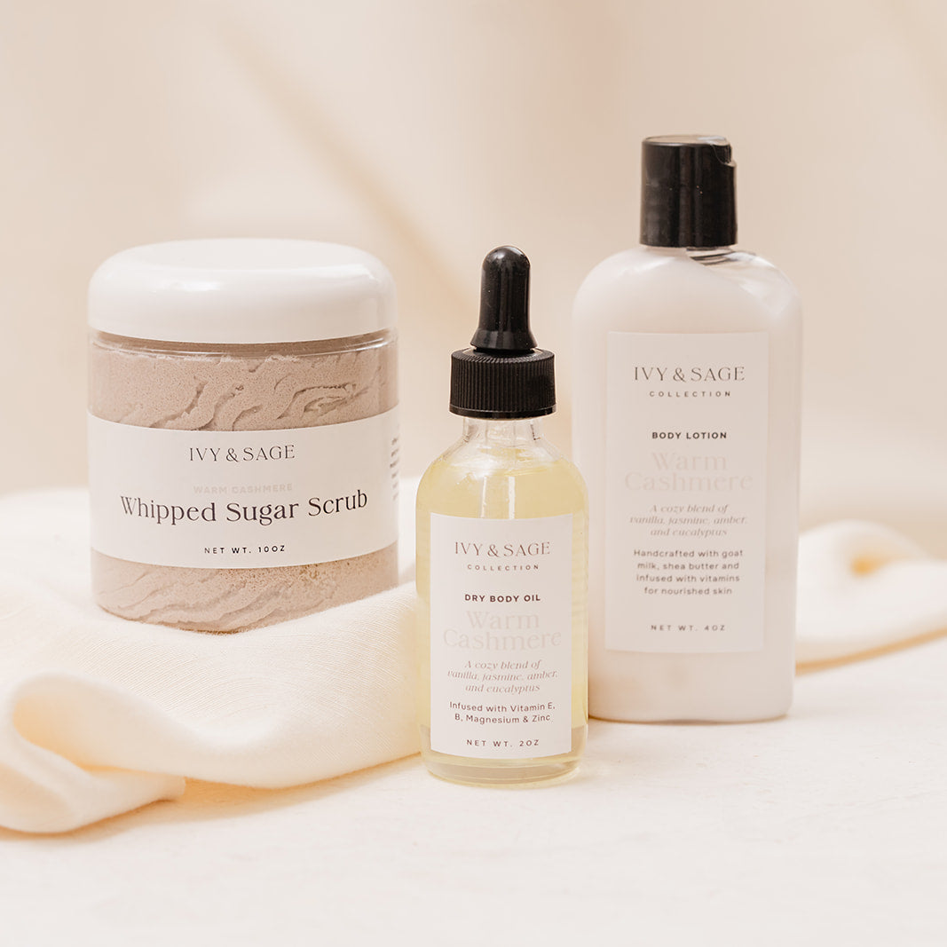 Ivy & Sage skincare products including a jar, dropper bottle, and lotion on a soft fabric background.