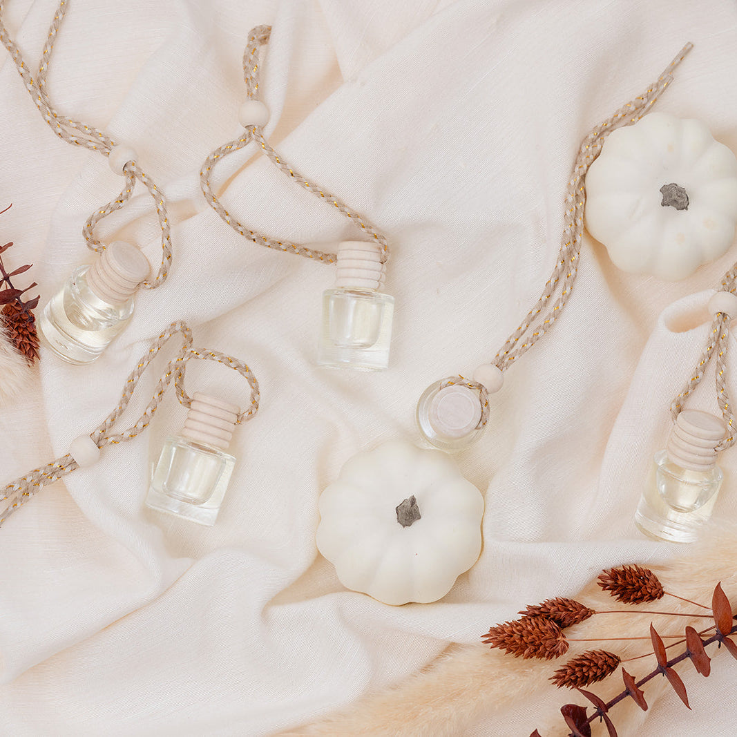 Glass Car Diffuser bottles and white pumpkins on a soft fabric background