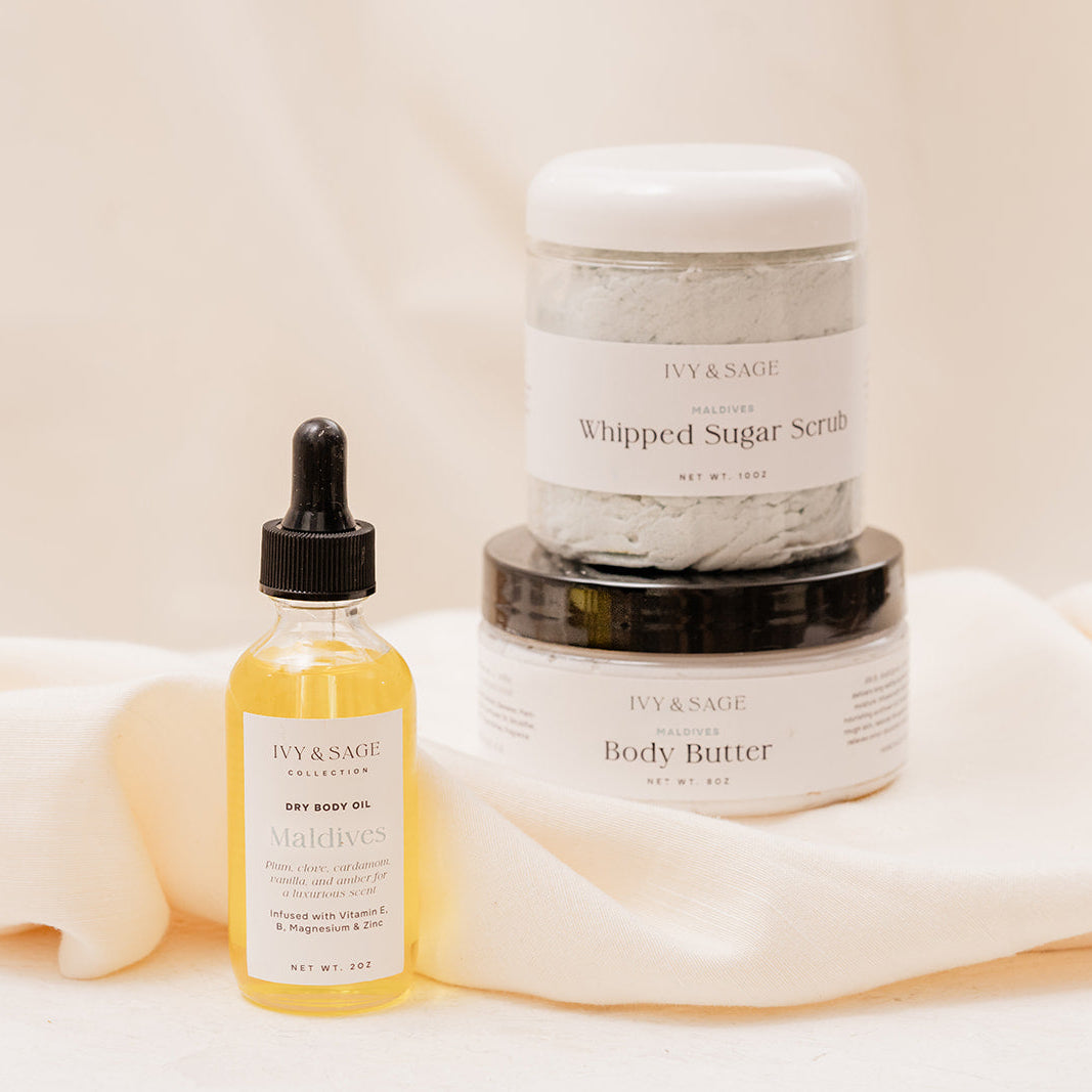 IVY & SAGE skincare products including a body oil, sugar scrub and body butter on a beige background