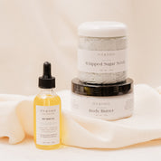 IVY & SAGE skincare products including a body oil, sugar scrub and body butter on a beige background