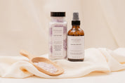 Two bottles of Ivy & Sage Bath Salts and Room Spray products on a light fabric background