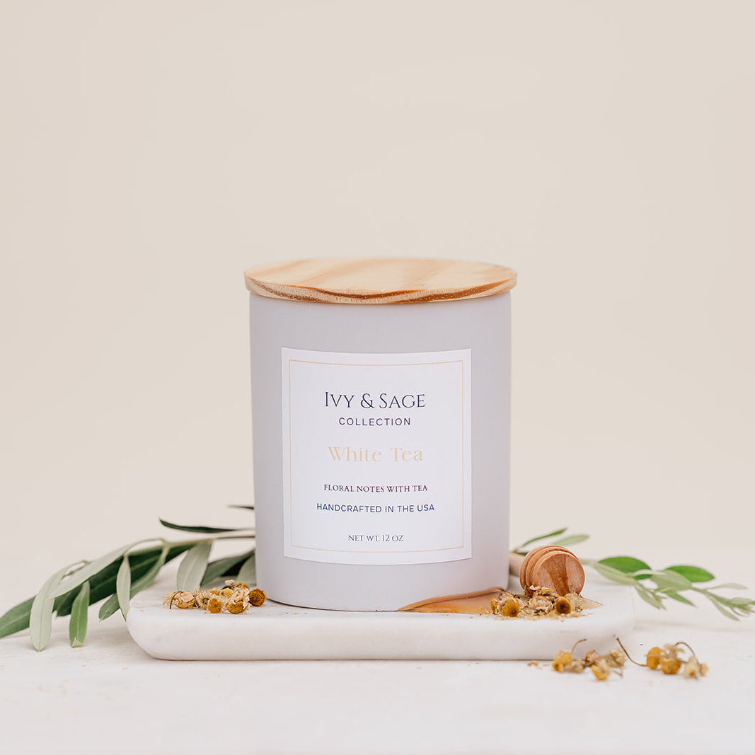 Ivy & Sage White Tea ceramic candle with wooden lid, styled with delicate botanicals and natural details.