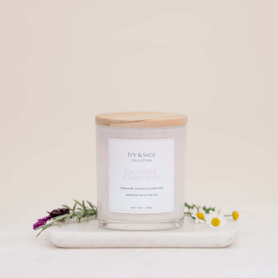 Ivy & Sage Lavender & Chamomile glass candle with wooden lid, styled with lavender and chamomile flowers.