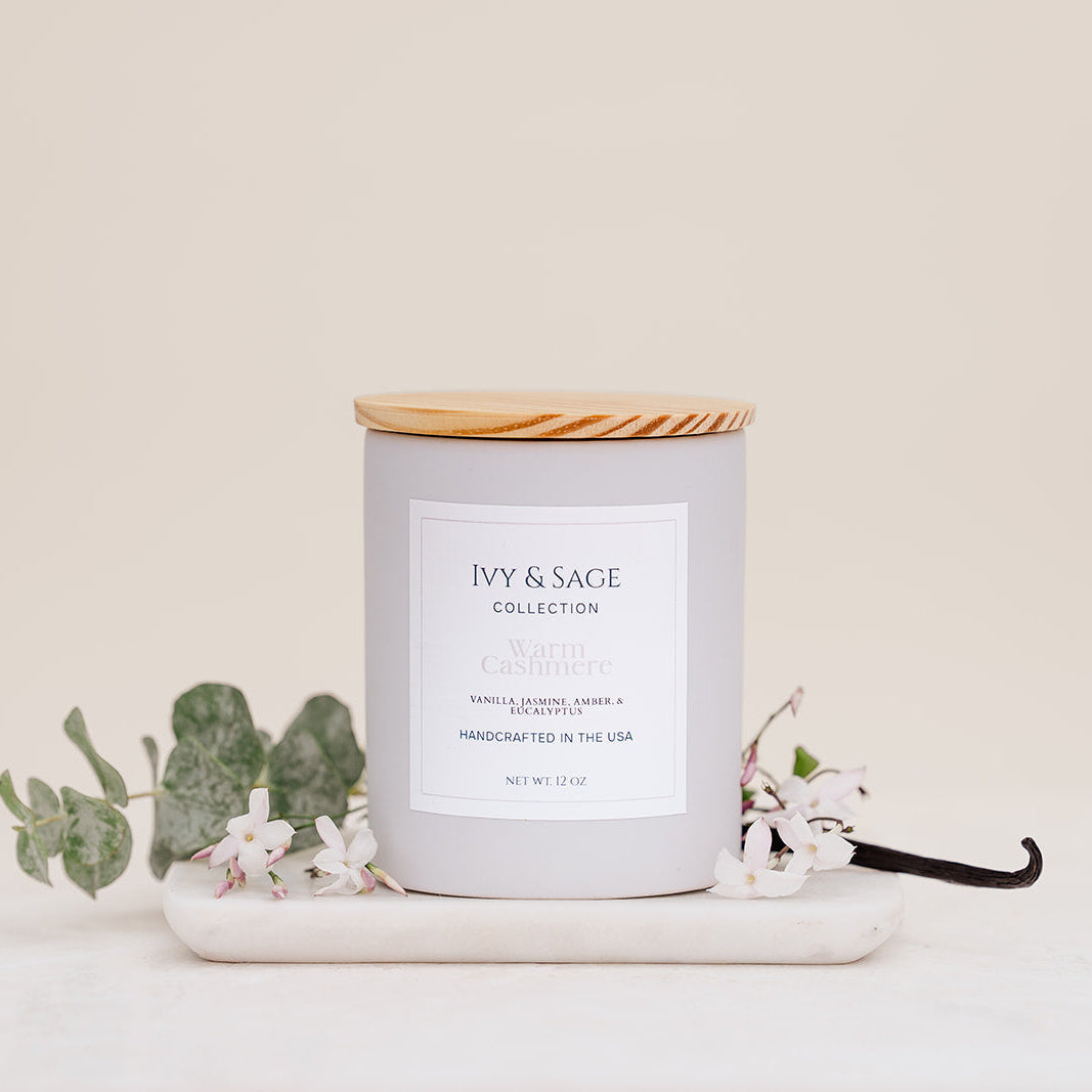 Ivy & Sage Warm Cashmere ceramic candle with wooden lid, styled with eucalyptus, jasmine flowers and vanilla.