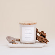 Ivy & Sage Santal 13 glass candle with wooden lid, styled with sandalwood and warm earthy botanicals.