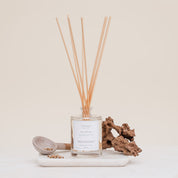 Ivy & Sage Santal 13 reed diffuser with natural reeds, styled with warm woody details on a neutral background.