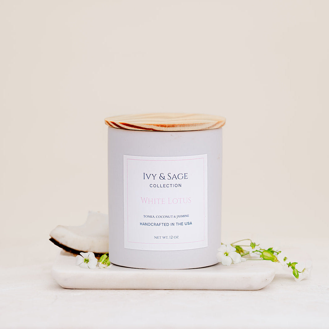 Ivy & Sage White Lotus ceramic candle with wooden lid, styled with coconut and delicate white flowers