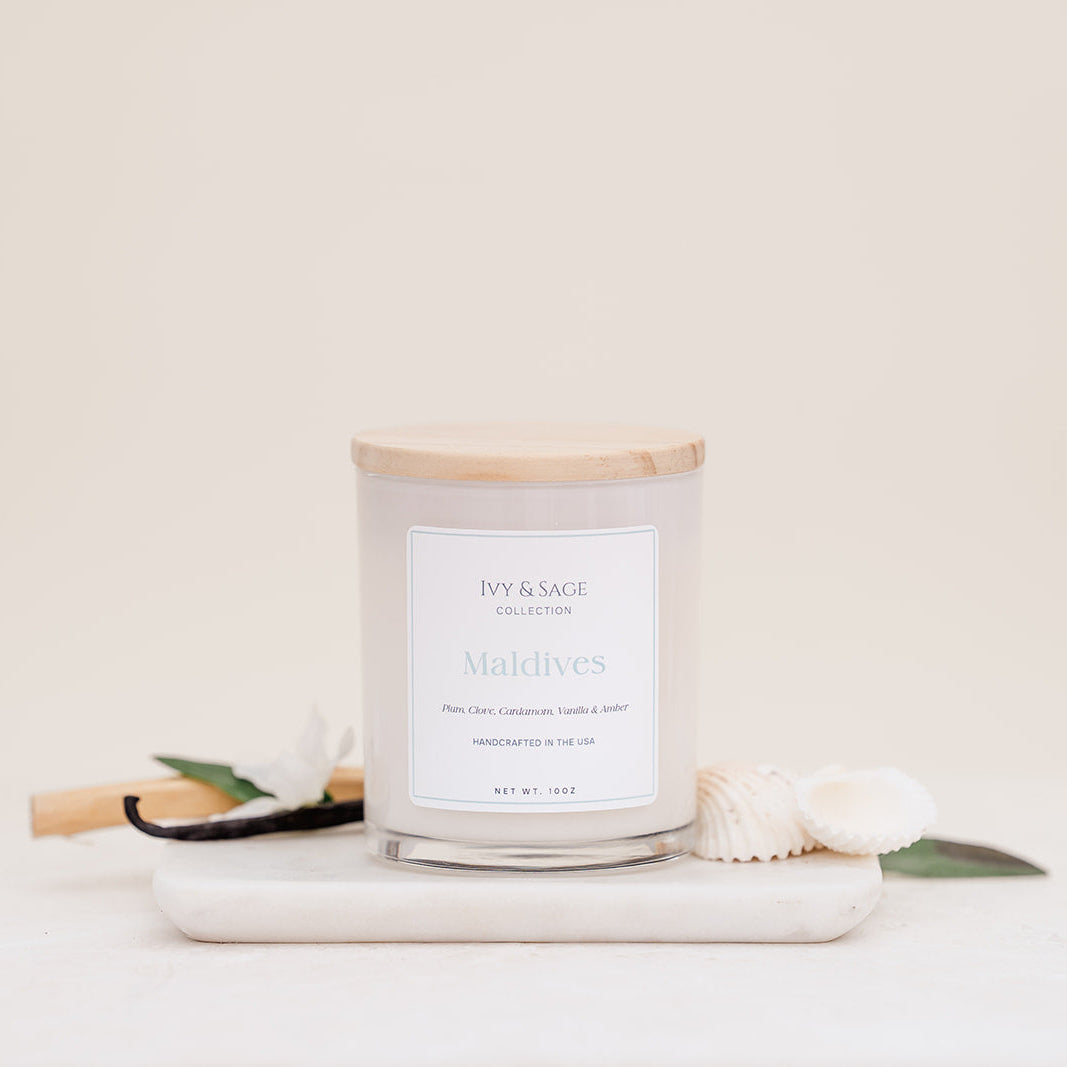 Ivy & Sage Maldives glass candle with wooden lid, styled with natural coastal-inspired details.