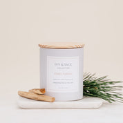 Ivy & Sage Palo Santo ceramic candle with wooden lid, styled with palo santo wood and fresh greenery.