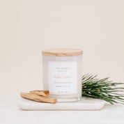 Ivy & Sage Palo Santo glass candle with wooden lid, styled with palo santo wood and fresh greenery.