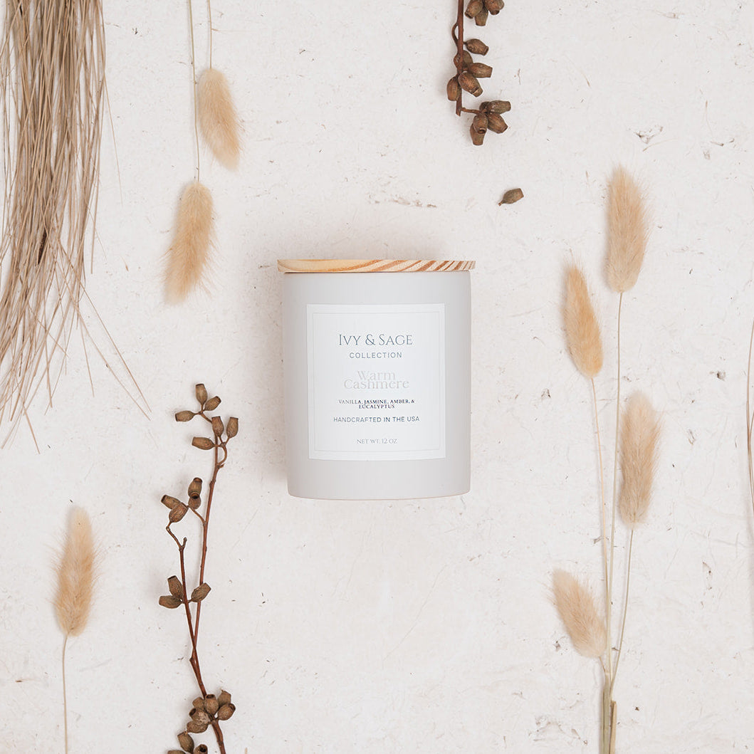 Ivy & Sage Warm Cashmere ceramic candle styled in a neutral botanical flat lay.