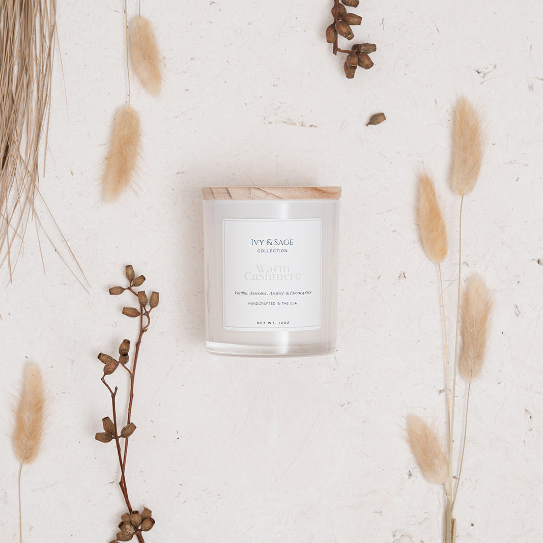 Ivy & Sage Warm Cashmere glass candle flat lay styled with soft neutral botanicals.