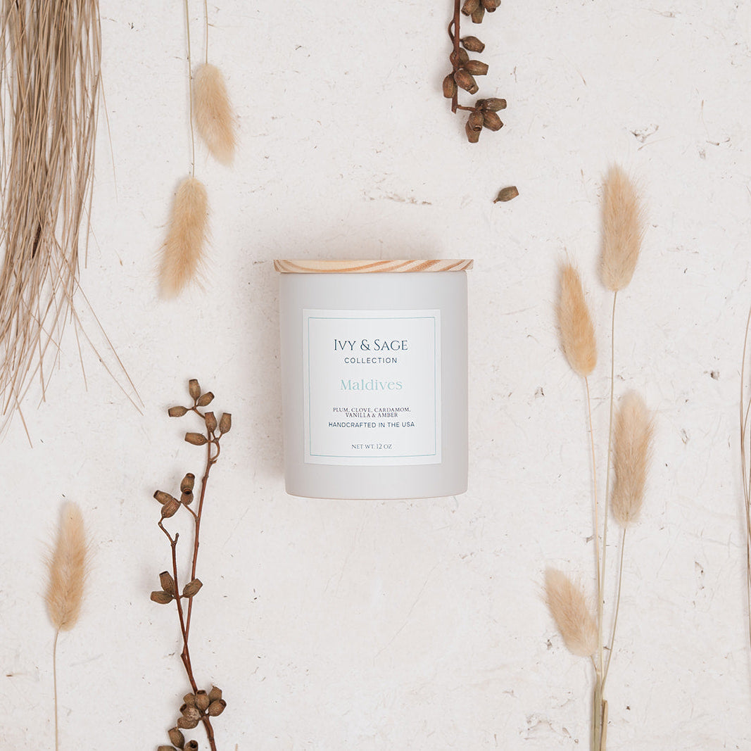 Ivy & Sage Maldives ceramic candle flat lay styled with neutral botanicals and natural textures.